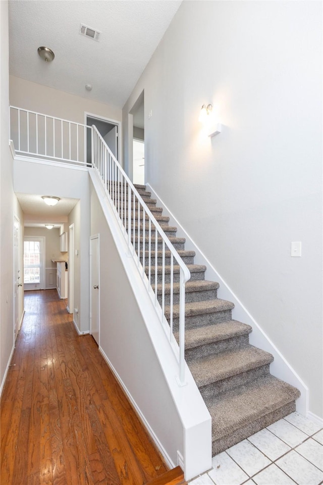 stairs with visible vents, baseboards, and wood finished floors