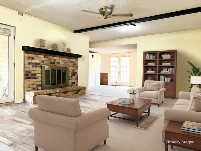 living room featuring a ceiling fan, a brick fireplace, and a textured ceiling