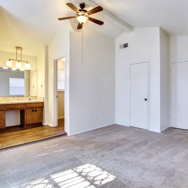 interior space featuring vaulted ceiling with beams, visible vents, light carpet, connected bathroom, and a textured ceiling