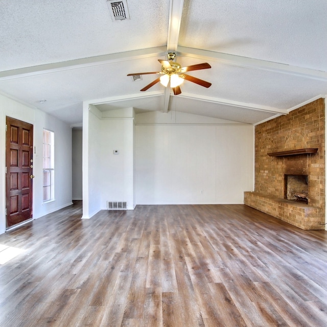 unfurnished living room featuring a textured ceiling, light wood finished floors, lofted ceiling with beams, and visible vents