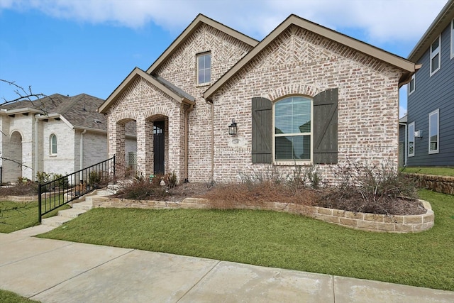 french country style house featuring a front yard, brick siding, and stairs