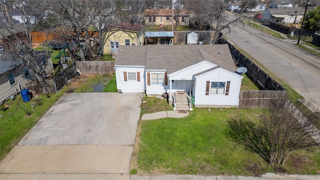 view of front of property with driveway, a residential view, roof with shingles, fence private yard, and a front yard