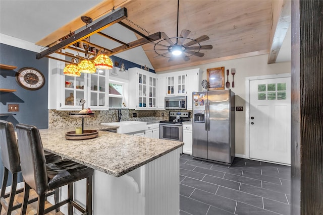 kitchen featuring backsplash, a peninsula, white cabinets, stainless steel appliances, and a ceiling fan