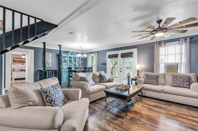 living area with plenty of natural light, ceiling fan with notable chandelier, stairway, and wood finished floors