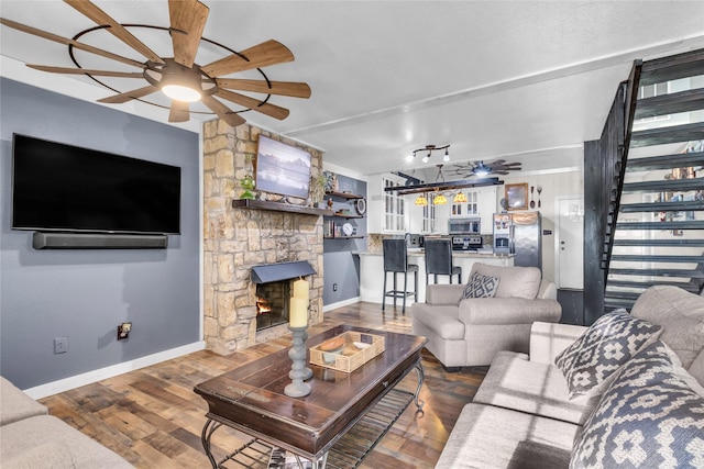living area with wood finished floors, stairway, a fireplace, baseboards, and ceiling fan
