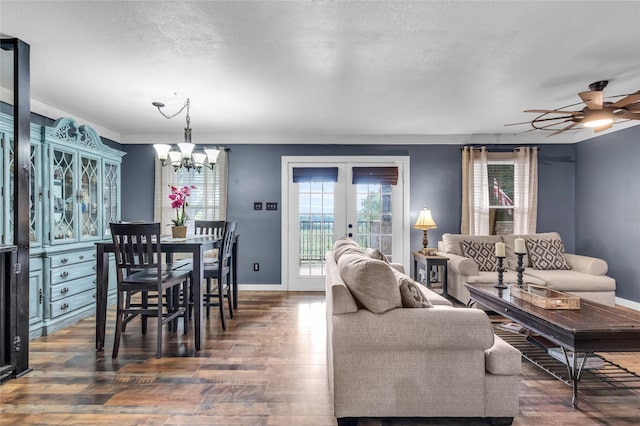 living room featuring ceiling fan with notable chandelier, wood finished floors, baseboards, and french doors