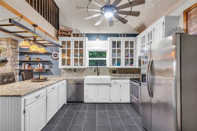kitchen featuring dark tile patterned flooring, a ceiling fan, a sink, appliances with stainless steel finishes, and a peninsula