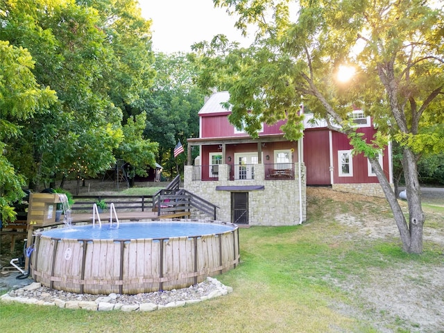 back of house featuring an outdoor pool, stairway, stone siding, and a lawn