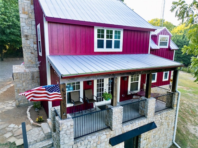 view of front of home with board and batten siding, a porch, french doors, metal roof, and stone siding