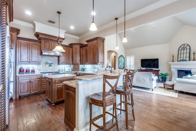 kitchen with a peninsula, a breakfast bar area, open floor plan, and hanging light fixtures