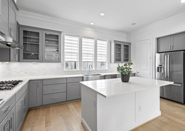 kitchen featuring light countertops, appliances with stainless steel finishes, a sink, and glass insert cabinets