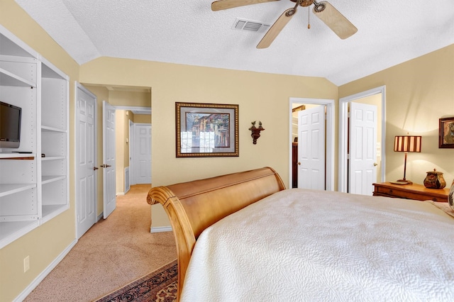 bedroom featuring vaulted ceiling, a textured ceiling, light carpet, and visible vents