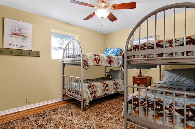 bedroom featuring ceiling fan, baseboards, and wood finished floors