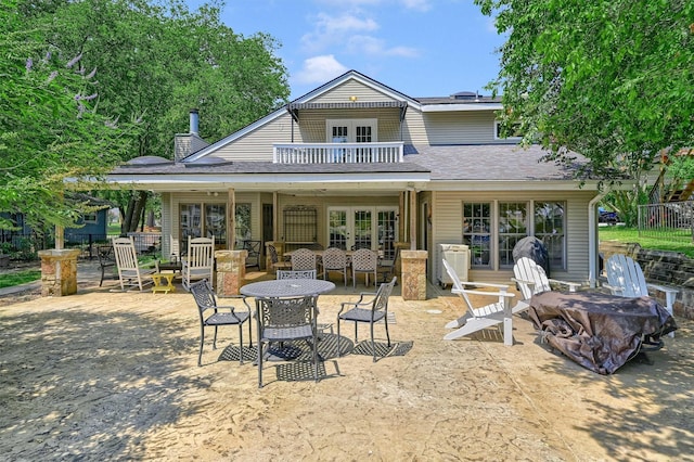 back of house featuring a balcony, a patio area, fence, and french doors