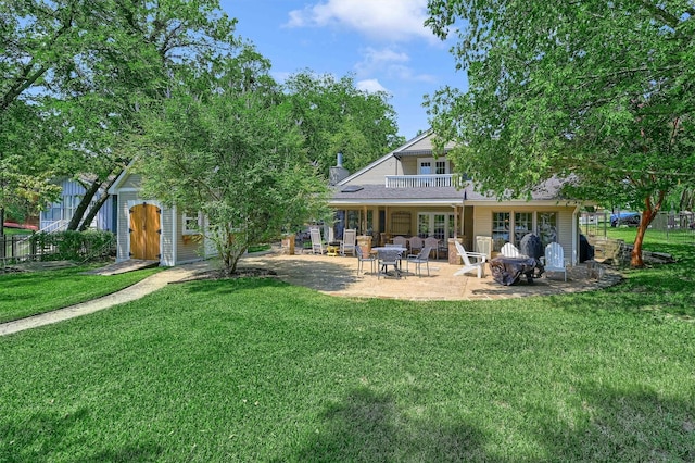 rear view of property featuring a yard, a patio, a balcony, and an outdoor structure