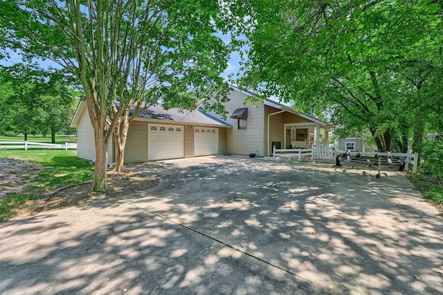 view of front of property with driveway, an attached garage, and fence