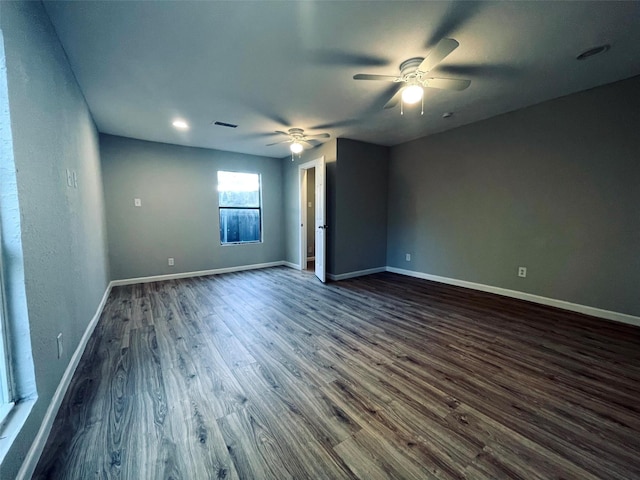 spare room featuring a ceiling fan, dark wood finished floors, visible vents, and baseboards