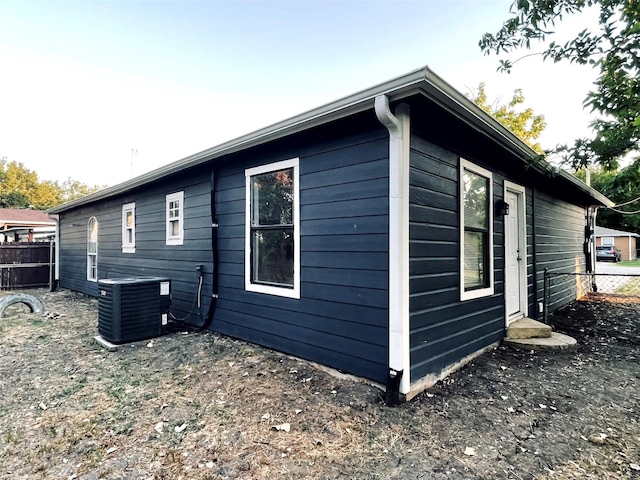 view of side of home featuring central AC unit and fence