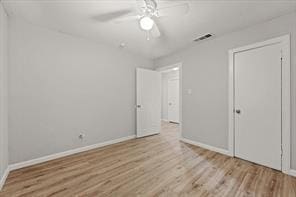 unfurnished bedroom featuring a closet, visible vents, light wood-style floors, ceiling fan, and baseboards