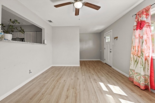 interior space featuring light wood-style flooring, visible vents, ceiling fan, and baseboards