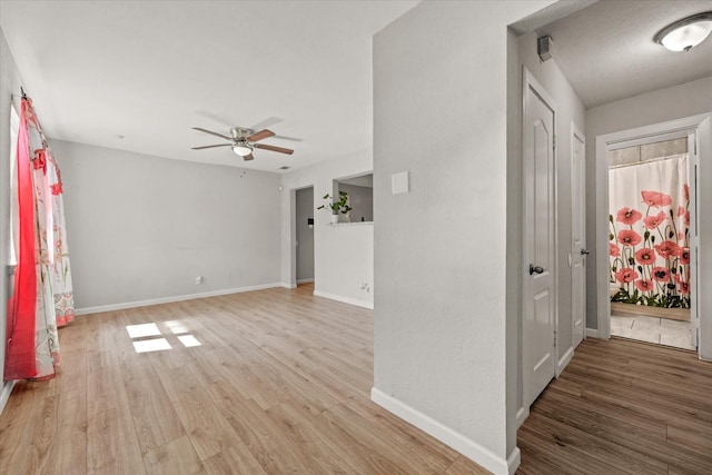 interior space featuring light wood finished floors, ceiling fan, and baseboards