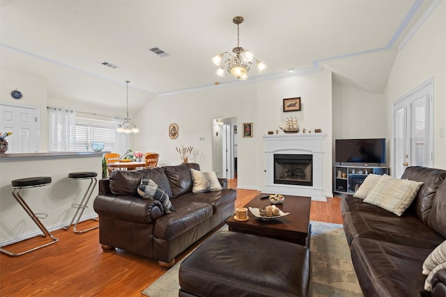 living area with vaulted ceiling, visible vents, and a chandelier