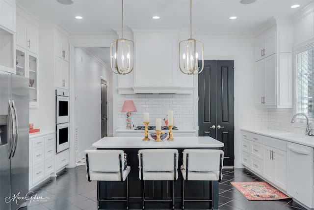 kitchen with appliances with stainless steel finishes, light countertops, a sink, and white cabinetry