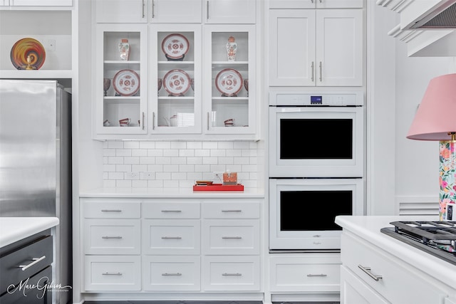 kitchen with white cabinets, appliances with stainless steel finishes, light countertops, and glass insert cabinets