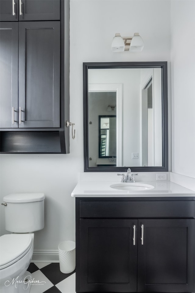 bathroom with baseboards, vanity, and toilet