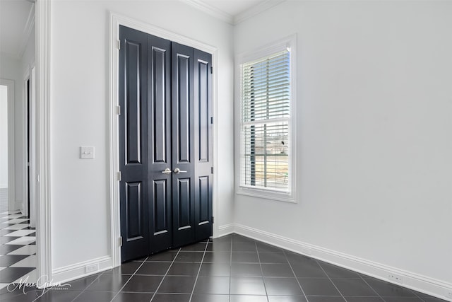 entrance foyer featuring dark tile patterned floors, baseboards, and crown molding