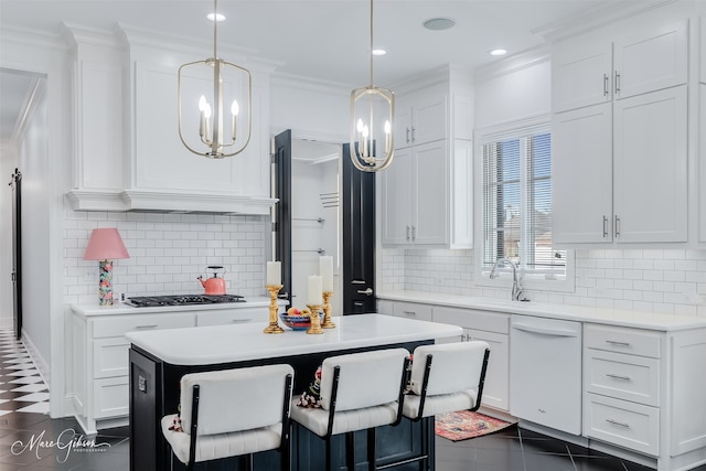 kitchen featuring light countertops, hanging light fixtures, white cabinetry, a kitchen island, and a sink