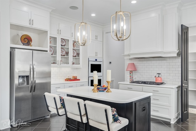 kitchen with stainless steel appliances, white cabinets, light countertops, a center island, and glass insert cabinets