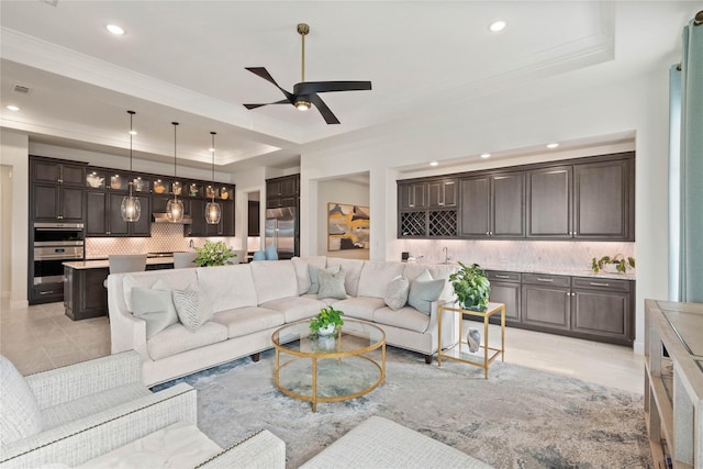 living room featuring a tray ceiling, crown molding, light tile patterned floors, recessed lighting, and a ceiling fan