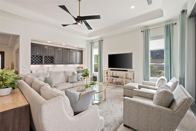 living room featuring wet bar, a tray ceiling, and a wealth of natural light