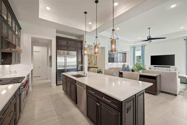 kitchen with high end appliances, light countertops, hanging light fixtures, glass insert cabinets, and under cabinet range hood