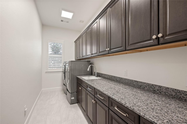 laundry area featuring washing machine and dryer, a sink, visible vents, baseboards, and cabinet space