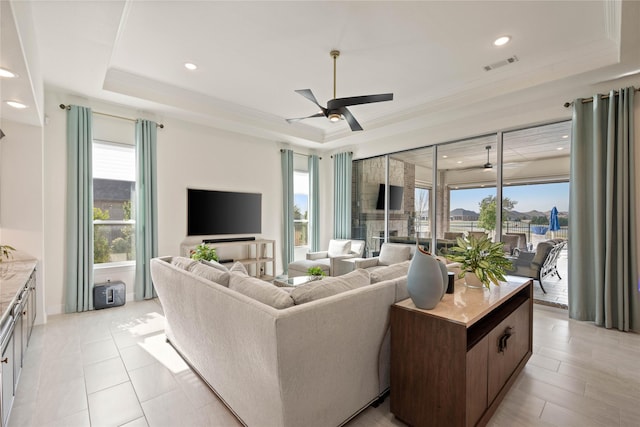 living room featuring a ceiling fan, a raised ceiling, and visible vents