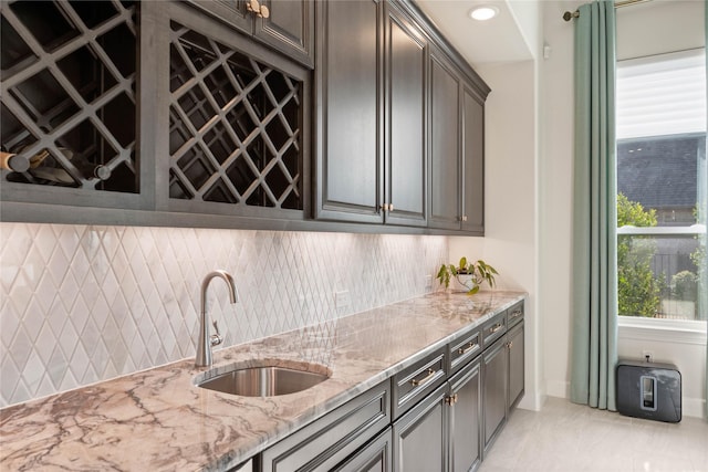 kitchen featuring light stone counters, tasteful backsplash, recessed lighting, a sink, and dark brown cabinets