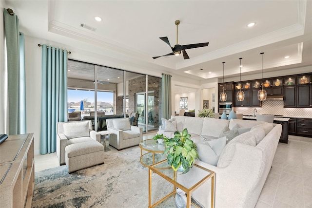 living room featuring visible vents, ceiling fan, a tray ceiling, crown molding, and recessed lighting