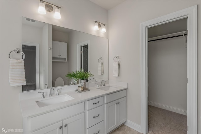 bathroom featuring visible vents, a sink, baseboards, and double vanity