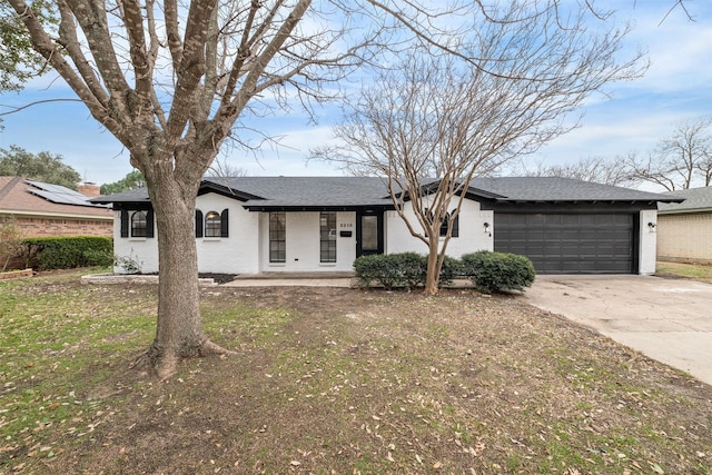 single story home featuring driveway, brick siding, roof with shingles, an attached garage, and a front yard