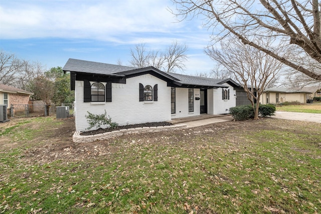 view of front facade with driveway, fence, a front yard, central AC, and brick siding