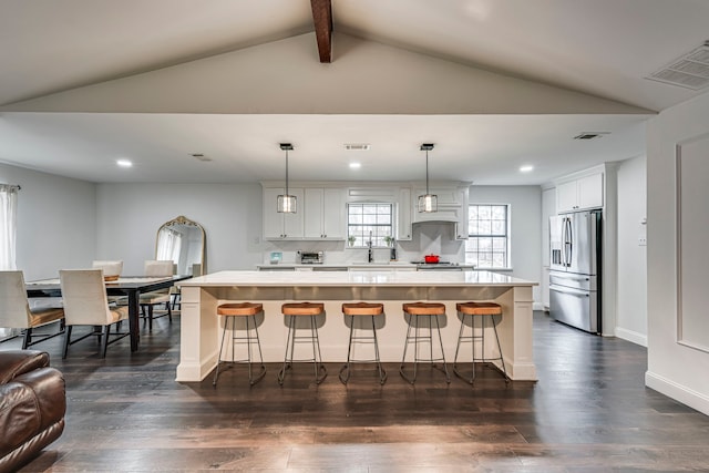 kitchen featuring white cabinets, a center island, light countertops, stainless steel refrigerator with ice dispenser, and pendant lighting