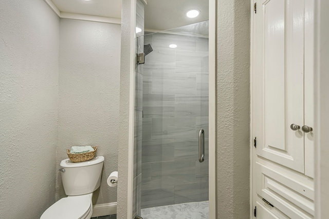 bathroom featuring toilet, a shower stall, and a textured wall