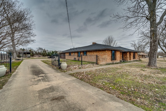 view of property exterior featuring brick siding, a fenced front yard, and a lawn