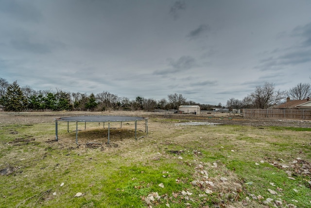 view of yard featuring a trampoline, a rural view, and fence