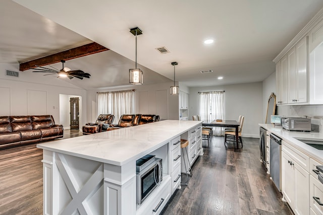 kitchen with stainless steel appliances, a kitchen island, white cabinetry, open floor plan, and hanging light fixtures