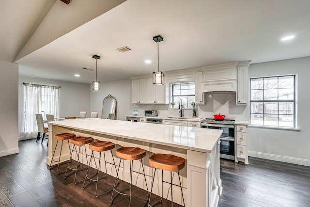 kitchen with a center island, decorative light fixtures, white cabinets, double oven range, and a kitchen breakfast bar