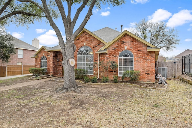 view of front of house with brick siding, fence, and central AC unit