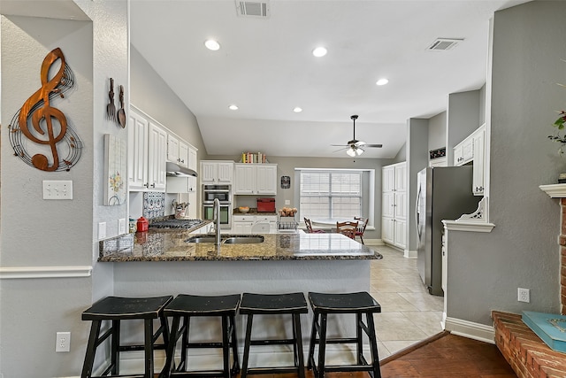 kitchen featuring a kitchen breakfast bar, a peninsula, a sink, and white cabinets